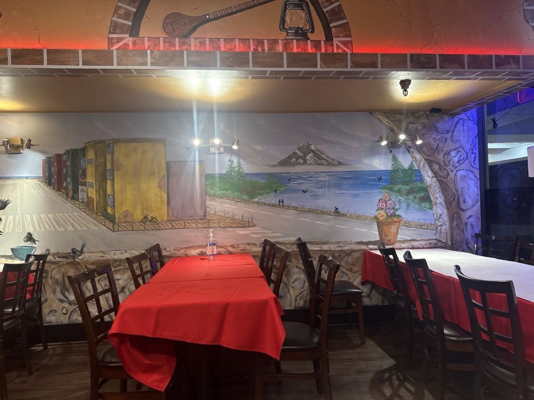 Turlock dining room with red tablecloths and a painted seaside mural